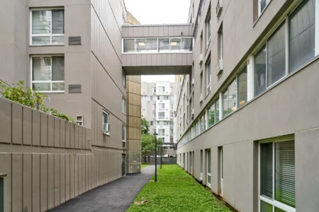 Pedestrian passage between The Landings buildings beneath an elevated enclosed walkway.