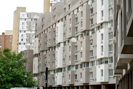 Street-level view along The Landings apartment buildings with trees and a taller residential tower beyond.